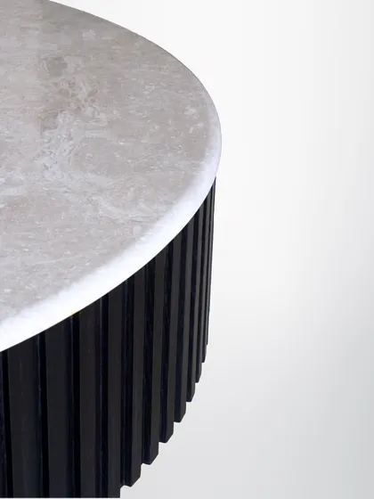 A close-up of the marble-topped table, highlighting the natural patterns in the stone and the precise craftsmanship of the fluted base.