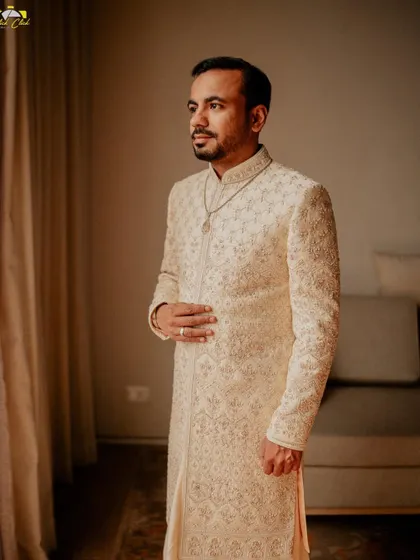 A classic portrait of the groom, looking dapper in his sherwani. The soft window light creates a timeless and sophisticated look.