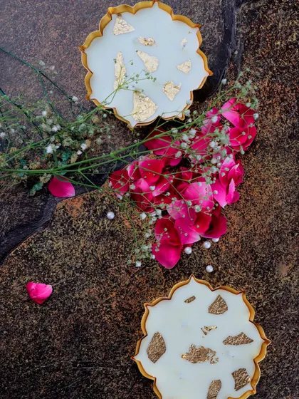An aerial view of two mini gold Urli candles, styled with rose petals and baby's breath, showcasing their decorative potential.