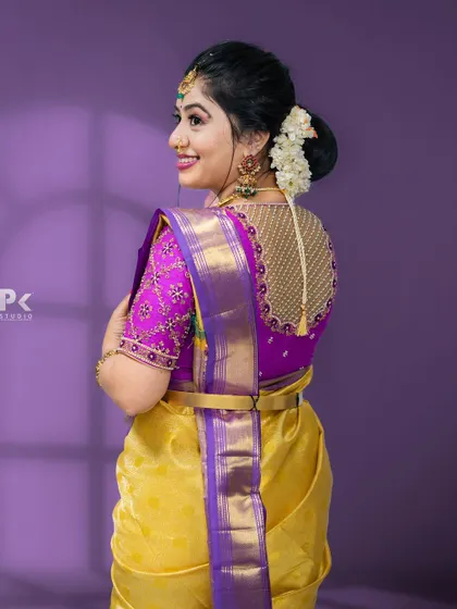 A stunning purple blouse with heavy gold embroidery on the back and sleeves, paired with a yellow Kanjeevaram saree.