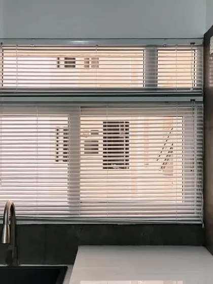 Stylish and practical Venetian blinds installed in a modern kitchen, offering privacy and easy light adjustment over the sink area.