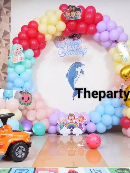 A fun Cocomelon party setup with a toy car and a colorful balloon ring.