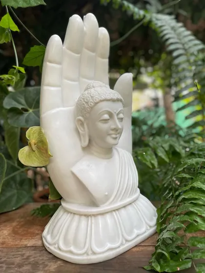 The incarnation of peace, this white marble statue features a Buddha bust held in a blessing hand, perfect for a tranquil garden or indoor setting.