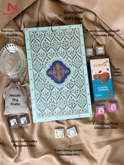 A flat-lay of a premium hamper. It includes a German silver basket, masala dry fruits, Loyka almond cookies, and an assortment of gourmet chocolate bites.