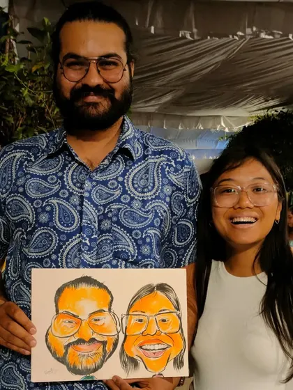 A happy couple from a collaborative event, posing with their colorful caricature.