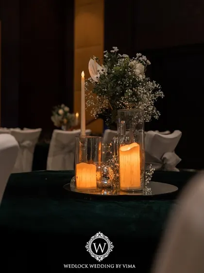 An elegant centerpiece for a Sangeet night, featuring white florals, baby's breath, and candles on a mirrored tray. The mini disco balls add a touch of sparkle and fun, tying into the party theme.