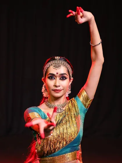 A close-up portrait in performance attire, focusing on the expressive storytelling conveyed through hand gestures (mudras) and facial expressions (abhinaya).