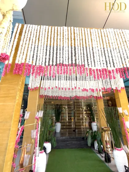 The view from inside the floral entrance, looking out. The dense curtain of white and pink flowers creates a beautiful frame and a sense of being enveloped in blooms as you enter the wedding venue.