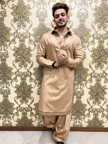 A full-length view of the beige Pathani suit, showing the traditional salwar-style trousers. The intricate embroidery on the cuffs and hem adds a touch of bespoke luxury.