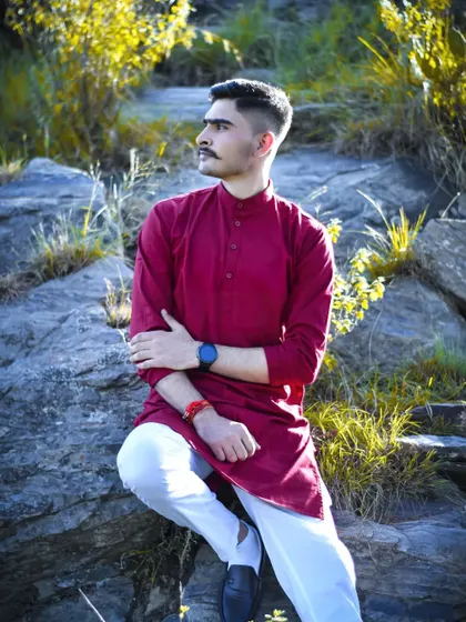 A relaxed, seated portrait of the groom. The warm sunlight and natural setting create a calm and contemplative mood.