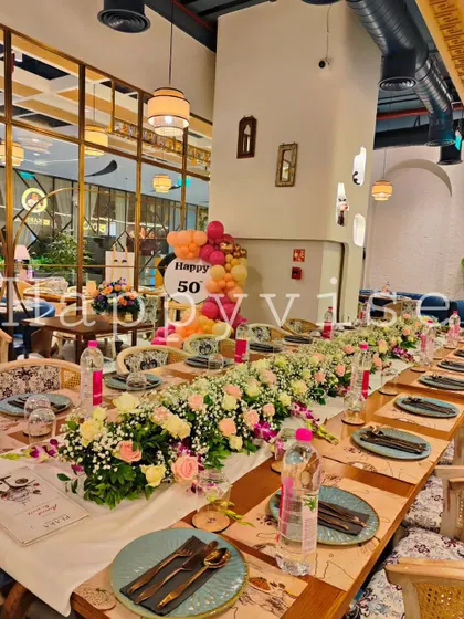 An elegant table setting for a 50th birthday dinner. The long table is adorned with a beautiful floral runner, showing my attention to detail extends to the entire event space.