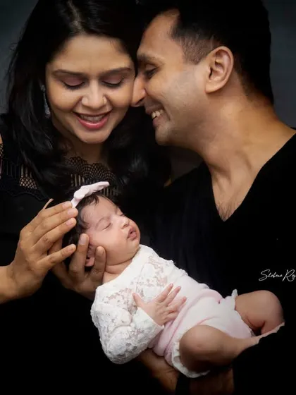 A candid moment from a newborn family photoshoot. The parents share a loving look while holding their sleeping baby, a perfect example of the gentle, emotional moments I aim to capture.