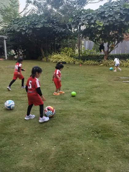 Players are spread out across the field, each practicing with a ball. This highlights our approach of giving each child ample opportunity to develop their individual skills during our sessions.