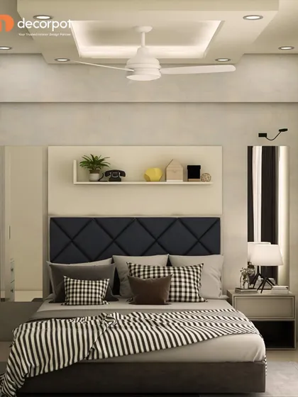 A chic and modern bedroom with a dark blue, diamond-patterned tufted headboard. The floating shelf above the bed provides a space for decor, while the mirrored panels make the room feel larger.