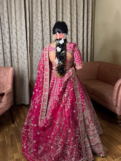 The back view of the bridal look, showing the detailed embroidery of the lehenga and the beautiful floral braid.
