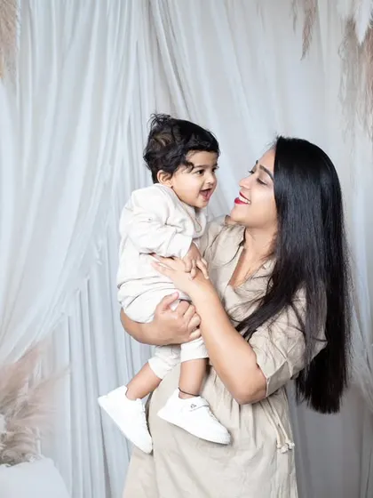 A mother and her baby share a sweet, smiling moment during their family photoshoot.