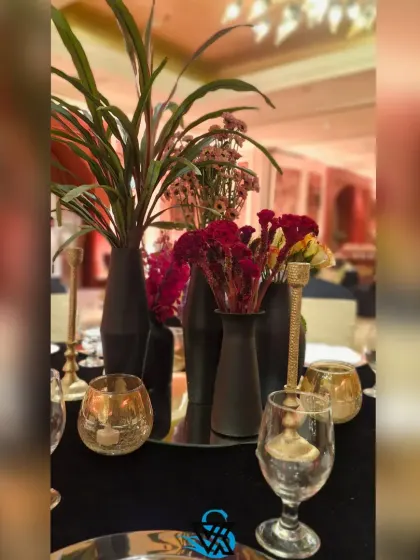 A modern table setting with black vases, dark linens, and pops of colorful flowers, creating a moody and sophisticated look.