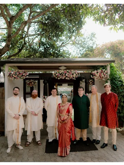 A formal group photo of the bride with the groom's side, showcasing the beautiful blend of their families on the wedding day.