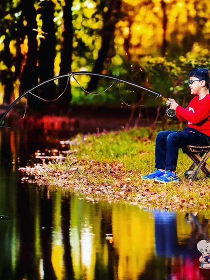 A creative and fun outdoor photo of a boy "fishing" by a lake. The beautiful reflection in the water and the imaginative setup make this a truly unique portrait.