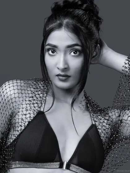 A direct and confident black and white portrait of the model in the bralette and mesh shrug, perfect for a portfolio headshot.