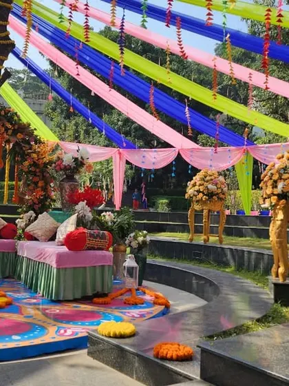 A wide view of the colorful Mehendi seating area, with bright drapes and low seating for a traditional and comfortable experience.
