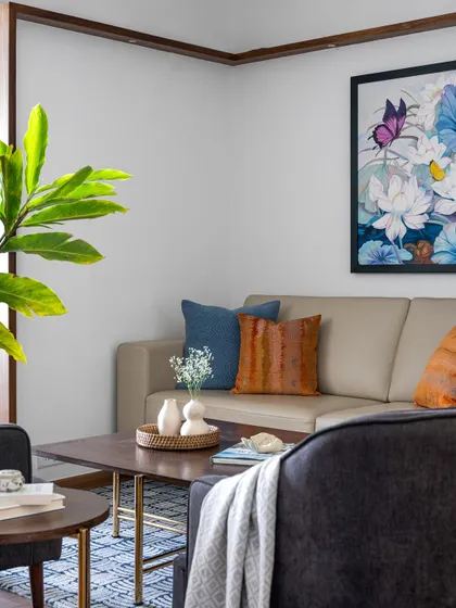 A cozy corner in the 'Pepper and Coffee' living room, where we used a mix of textures and colors, like the leather sofa and vibrant cushions, to create a warm and personal feel.