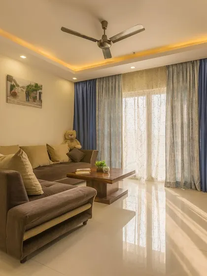 The L-shaped sofa provides ample seating, while the simple wooden coffee table and soft lighting create a cozy and inviting atmosphere.