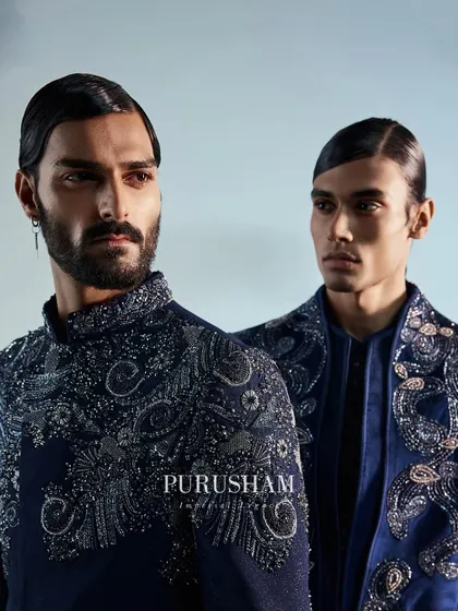 A close-up of two navy blue velvet jackets, showcasing the dazzling and irresistible allure of the hand embroidery. The detail work is designed to catch the eye and hold it.