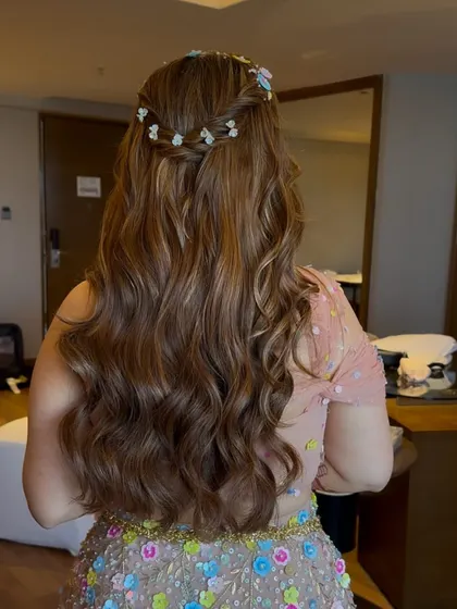 A back view of the half-updo with a delicate braided crown adorned with tiny flowers. The highlights in the hair add beautiful dimension to the waves.