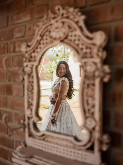 A stunning bride in a white lehenga, exuding grace and elegance. We use creative framing and lighting to capture a variety of beautiful portraits.