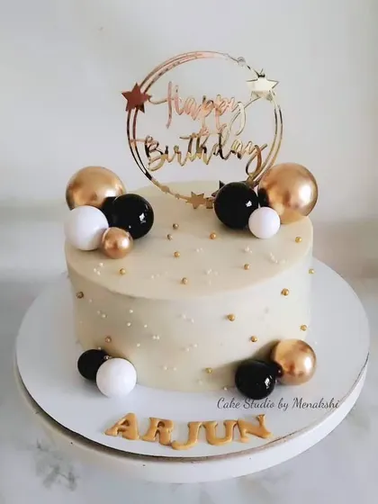 A classy and elegant birthday cake in a timeless black, white, and gold color scheme. This design is completely without fondant, decorated with spheres and a custom topper.