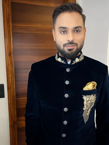 A close-up of a groom styled in a luxurious navy velvet bandhgala. The detailed grooming of his beard and hair complements the rich texture and gold embroidery of the outfit.