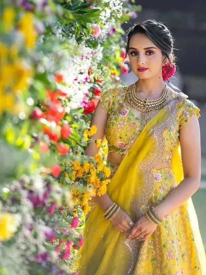 A perfect Haldi ceremony look. The bright yellow lehenga and floral jewellery are complemented by fresh, dewy makeup with a pop of pink on the lips.