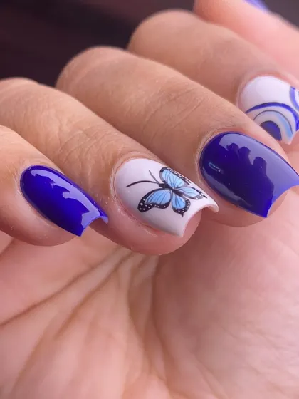 This angle shows the contrast between the bold blue and the delicate butterfly art, a perfect manicure for summer.