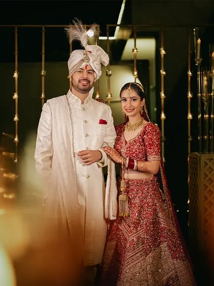 A classic portrait of the bride and groom, perfectly framed by the blurred candles, creating a sense of depth and warmth.