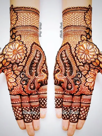 An Indian designer mehendi with a mix of floral and peacock motifs. The combination of bold figures and delicate net patterns creates a balanced and beautiful look.