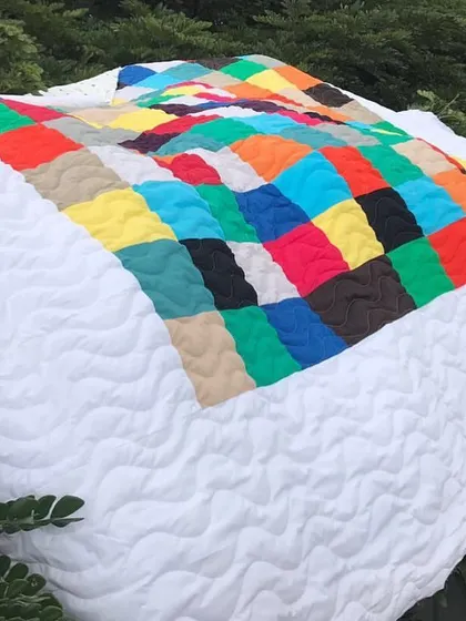 A modern color-block quilt displayed outdoors, showing its vibrant colors against a natural backdrop.