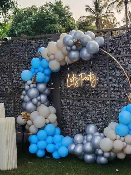 Let's party! This stylish outdoor setup features a circular balloon garland in shades of blue and silver with a neon sign, creating a perfect photo spot for any modern celebration.