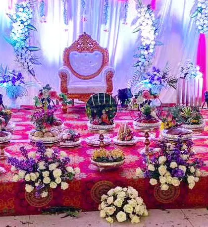 This wide shot shows the setup process for a grand ceremony. You can see the stage with its purple and white theme, the throne chair, and the numerous decorative trays being arranged to create the final, stunning look.