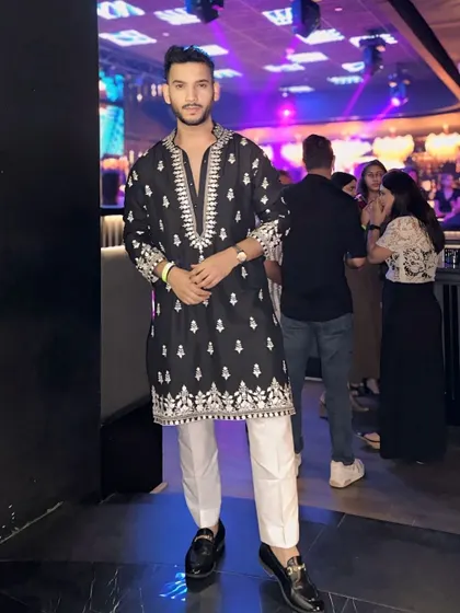 This black kurta with white embroidery, paired with crisp white trousers, is a classic combination for a Dandiya night or any festive gathering. It's traditional with a modern edge.