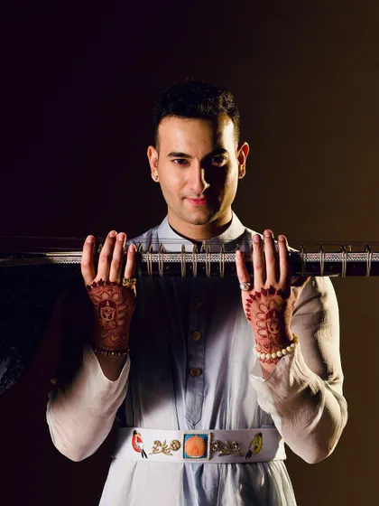 A stylish portrait celebrating a milestone, with henna-adorned hands holding the sitar.