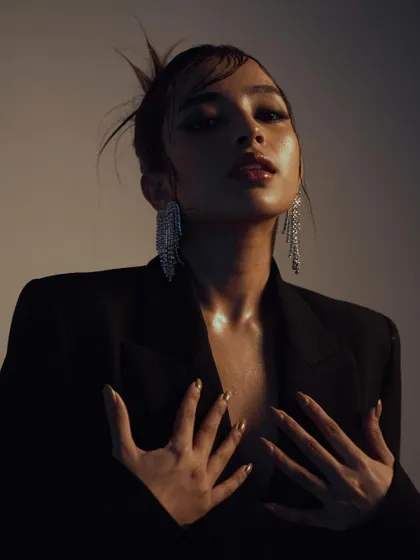 An intimate and expressive close-up. The warm, soft lighting and the model's pose create a sensual and glamorous mood, perfect for a beauty or jewelry campaign.