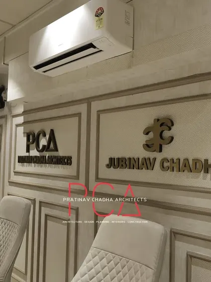 A shared office space within the Jubinav Chadha studio, featuring classic wall mouldings and dual branding for PCA and the fashion label.