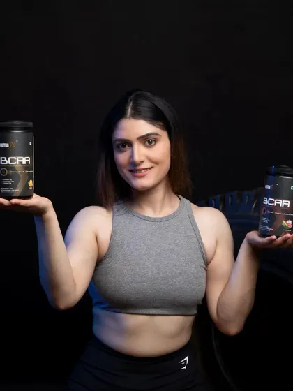 A female model showcasing two different flavors of BCAA supplements, helping customers compare options.