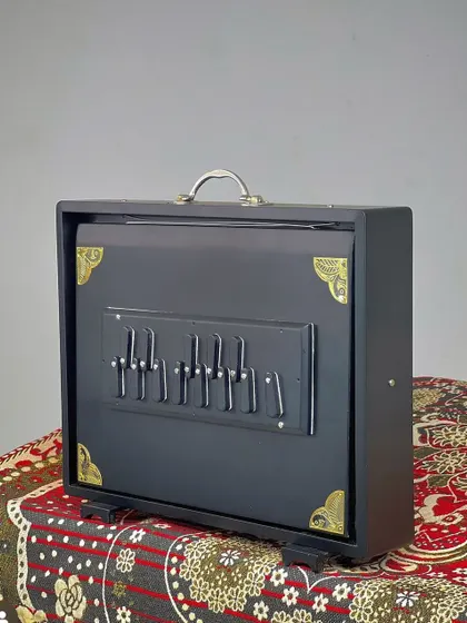 A traditional manual Shruthi Box, or surpeti. This instrument provides a constant drone to support vocalists and instrumentalists during practice and performance, essential for maintaining pitch.