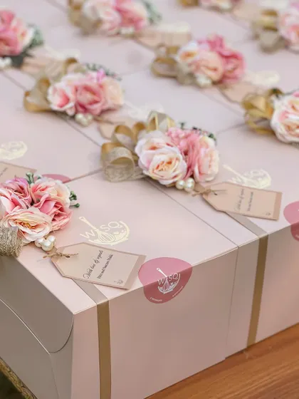 A detailed look at the handcrafted toppers on our return favour boxes. Each one includes a mix of faux flowers, pearls, and a gold ribbon, along with a personalized "Thank you for your love" tag.