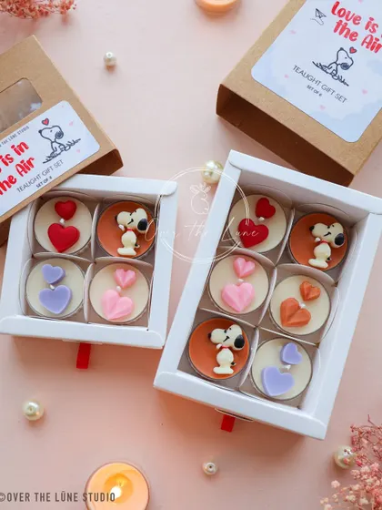 Both the 4-piece and 6-piece Snoopy tealight gift sets. The kraft paper boxes give them a charming, rustic feel.