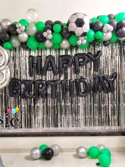 An 18th birthday football-themed decoration with a green, black, and silver balloon arch against a shimmer curtain.