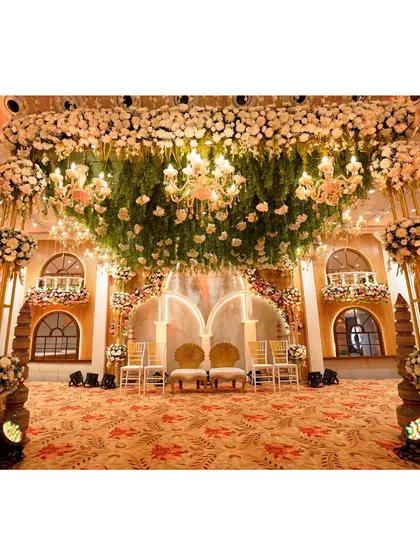 A wider view of the royal-themed stage, showcasing the beautiful floral arch and elegant seating for the bride and groom.
