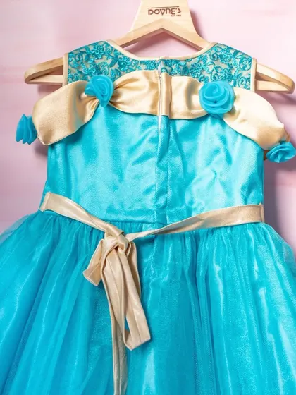 A closer look at the back of this stunning turquoise tulle gown. It features delicate floral details on the shoulders and a simple tie-back sash for a perfect fit.